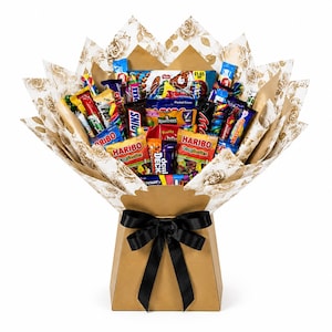 May include: A bouquet arrangement of assorted candy bars and snack bags, including Haribo Tangfastics, Snickers, and Rowntrees, wrapped in cream-coloured paper with a floral pattern. The bouquet is held in a tan cardboard base tied with a black ribbon.