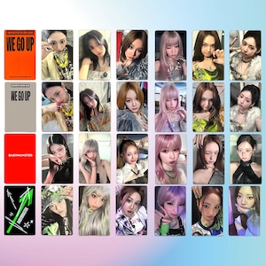 May include: A collection of rectangular photo cards featuring members of the K-pop group BABYMONSTER. The cards have various images of the group members, with some cards displaying the album title "WE GO UP" and the group's name.