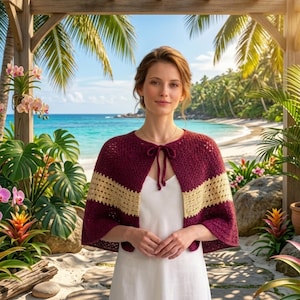 May include: A burgundy and tan crochet cape with a tie closure. The cape is worn over a white dress. The background features a tropical beach scene with palm trees and blue water.