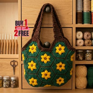 May include: A handmade crochet tote bag with a dark brown handle and trim. The bag features a green hexagonal pattern with yellow flower accents. The text "BUY 1 AND GET 2 FREE" is visible.