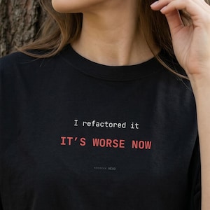 以下が含まれることがあります： 白と赤で「I refactored it, it's worse now」と書かれた黒いTシャツ。 このシャツは半袖のクルーネックです。