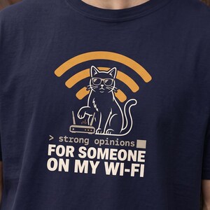 May include: A navy blue t-shirt featuring a graphic of a cat wearing sunglasses sitting next to a Wi-Fi router with a yellow Wi-Fi signal icon above it. The text reads: > strong opinions FOR SOMEON ON MY WI-FI in white and light gray lettering.