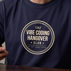 Puede incluir: Una camiseta de manga corta azul marino con un gráfico circular de color crema en el pecho. El texto dentro del círculo dice THE VIBE CODING HANGOVER CLUB, con EST 2025 y MEMBERS: EVERYONE impresos debajo de las dos pequeñas estrellas.