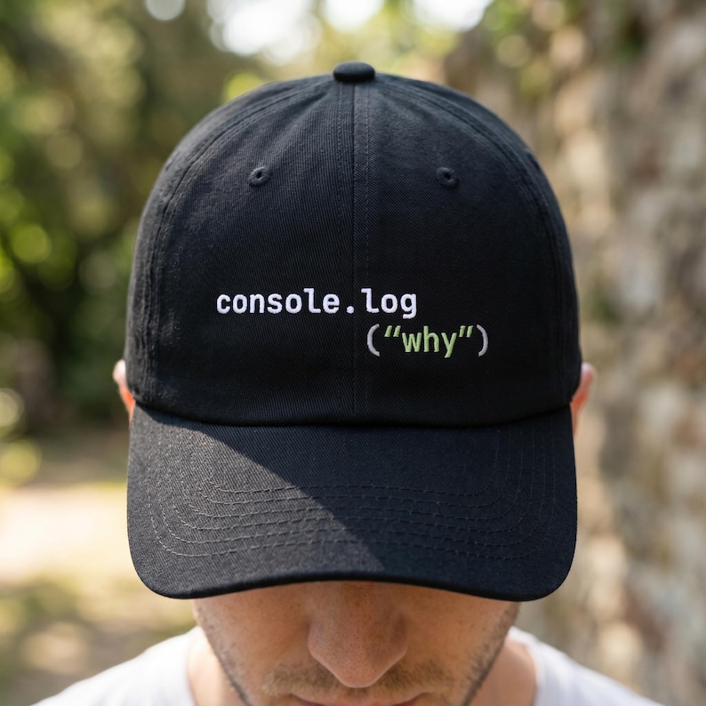 May include: Black baseball cap with the text "console.log ("why")" in white and green. The cap is made of a soft material and has a curved brim. A casual accessory for everyday wear.
