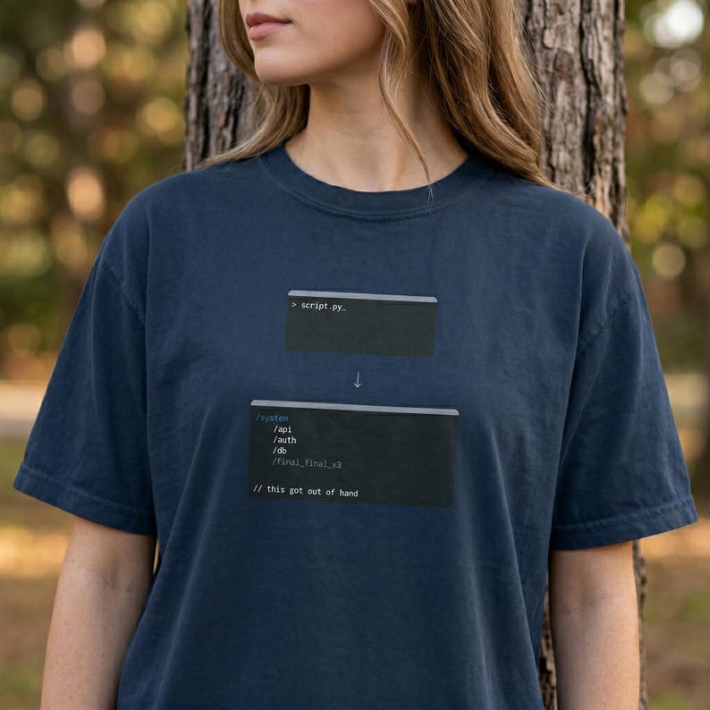 May include: Navy blue t-shirt featuring a programming-themed graphic. The design includes code snippets, the text '> script.py.' and '// this got out of hand', and a downward arrow, giving a tech-inspired look.