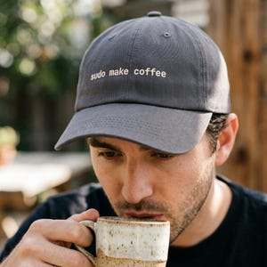 Pu&ograve; includere: Un cappellino da baseball grigio con la scritta "sudo make coffee" ricamata in bianco. Il cappellino &egrave; realizzato in tessuto morbido e ha una visiera curva. Un accessorio casual.
