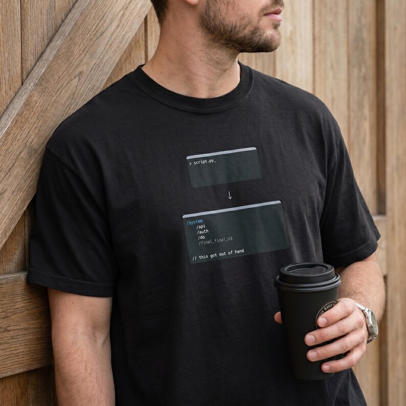 May include: Black t-shirt featuring a programming-themed graphic with code snippets and the text "script.py" and "// this got out of hand". The design includes a downward arrow and lines of code.