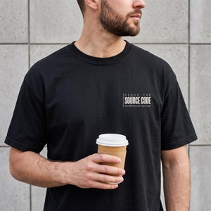 May include: A black short-sleeved t-shirt featuring white text on the chest that reads "READS THE SOURCE CODE" with the smaller text "documentation optional" underneath. The shirt has a crew neckline and a standard fit design.