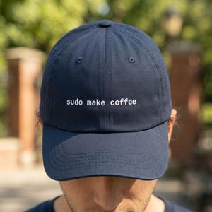 Pu&ograve; includere: Cappellino da baseball blu navy con la scritta "sudo make coffee" ricamata in bianco. Il cappellino ha una visiera curva e un classico design a sei pannelli. Un accessorio casual.