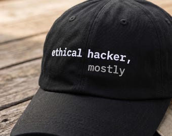 May include: A black baseball cap featuring the embroidered white text "ethical hacker," with the word "mostly" embroidered in a smaller, light gray font directly underneath the first line of text on the front panel.