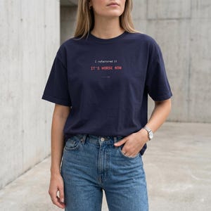 Puede incluir: Camiseta azul marino con el texto "I refactored it, IT'S WORSE NOW" en rosa y blanco. La camiseta es de corte holgado y se combina con vaqueros azules. El estilo es casual y moderno.