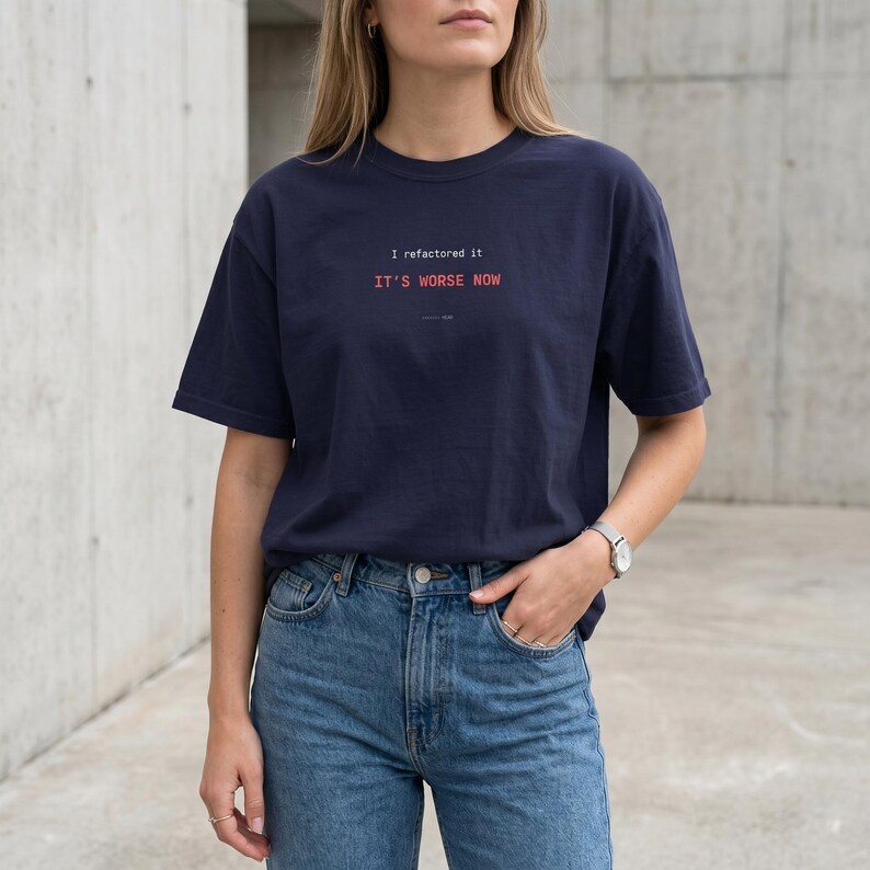 Puede incluir: Camiseta azul marino con el texto "I refactored it, IT'S WORSE NOW" en rosa y blanco. La camiseta es de corte holgado y se combina con vaqueros azules. El estilo es casual y moderno.