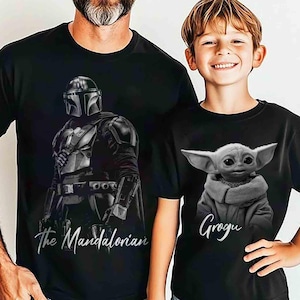 May include: Two black t-shirts featuring characters from The Mandalorian. One shirt displays the Mandalorian with the text "The Mandalorian." The other shirt shows Grogu with the text "Grogu."