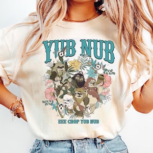 May include: A cream-coloured t-shirt with the teal text "YUB NUB" above a graphic of Ewoks and flowers. Below the graphic is the text "EEE CHOP YUB NUB". The design has a vintage, retro aesthetic.