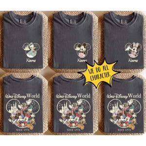 May include: Dark grey t-shirts featuring Disney character graphics. Top row shows Donald Duck, Mickey Mouse, and Minnie Mouse in circular outlines with the text Name. Bottom row shows a group of Disney characters with Walt Disney World Since 1971.