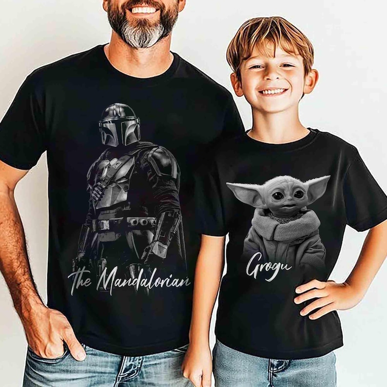 May include: Two black t-shirts featuring characters from The Mandalorian. One shirt displays the Mandalorian with the text "The Mandalorian." The other shirt shows Grogu with the text "Grogu."
