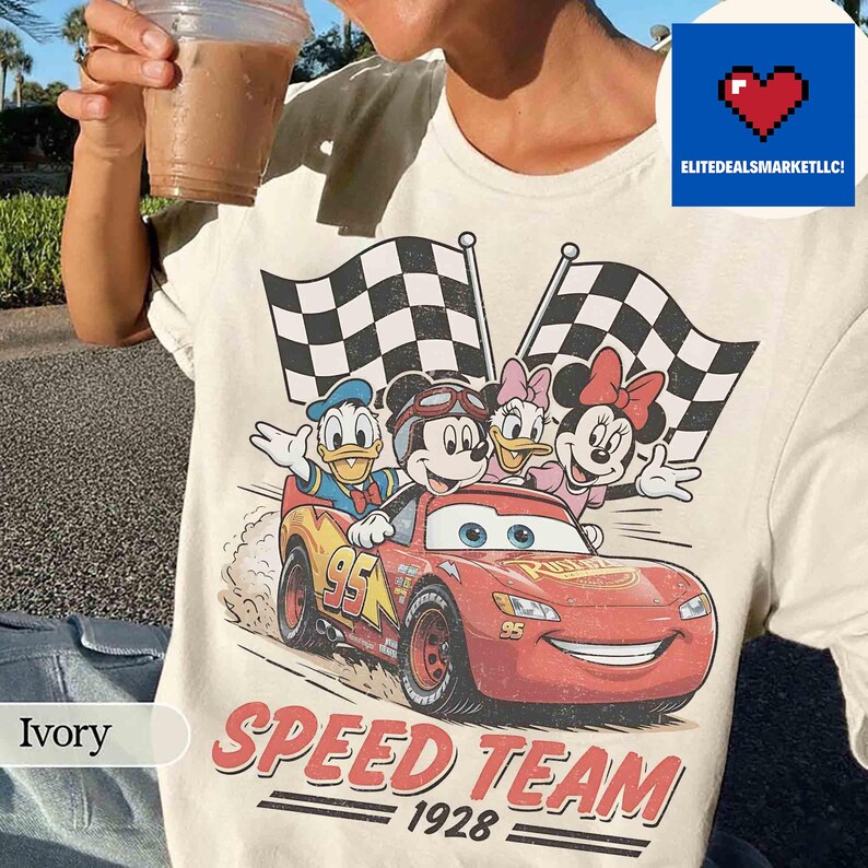 Pu&ograve; includere: T-shirt color avorio con grafica di Topolino, Paperino, Paperina e Minni in un'auto da corsa rossa. L'auto ha il numero 95. La maglietta riporta anche la scritta "SPEED TEAM 1928".