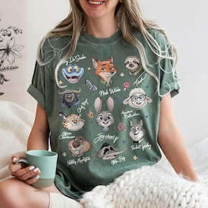 K&ouml;nnte beinhalten: Gr&uuml;nes T-Shirt mit Cartoon-Charakterportr&auml;ts aus Zootopia. Das Shirt zeigt Charaktere wie Nick Wilde, Judy Hopps und Flash. Das Design ist auf einem gr&uuml;nen T-Shirt mit kurzen &Auml;rmeln aufgedruckt.