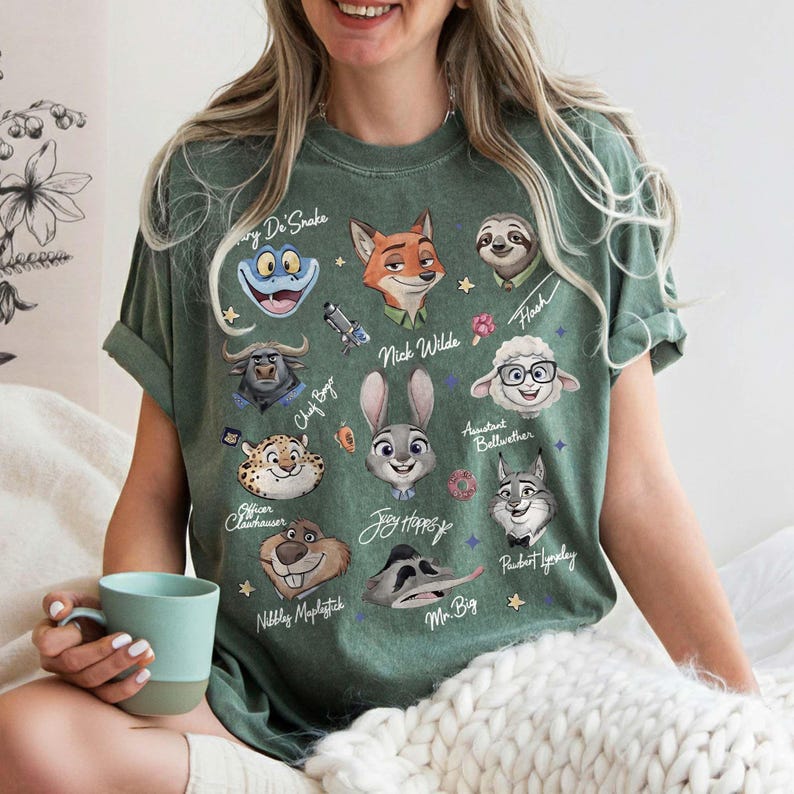 K&ouml;nnte beinhalten: Gr&uuml;nes T-Shirt mit Cartoon-Charakterportr&auml;ts aus Zootopia. Das Shirt zeigt Charaktere wie Nick Wilde, Judy Hopps und Flash. Das Design ist auf einem gr&uuml;nen T-Shirt mit kurzen &Auml;rmeln aufgedruckt.