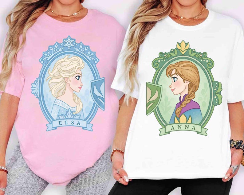 May include: Two t-shirts, one pink and one white, each featuring a cartoon portrait of a princess. The pink shirt has Elsa's portrait, while the white shirt has Anna's portrait. Both portraits are framed with decorative elements and names.