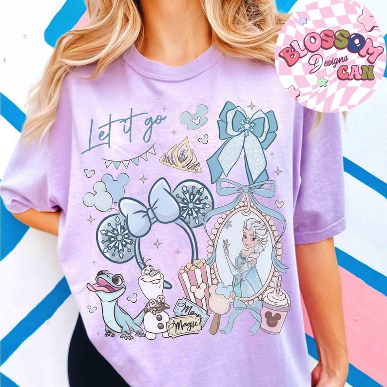 Może przedstawiać: Jasnofioletowa koszulka z nadrukiem graficznym z napisem "Let it go". Projekt zawiera obrazy księżniczki, płatk&oacute;w śniegu i postaci z kresk&oacute;wek. Koszulka ma kr&oacute;tkie rękawy.