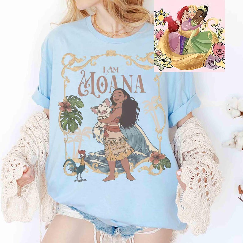 May include: Light blue t-shirt featuring a graphic of Moana holding a pig, with the text "I AM MOANA." The design includes floral and wave elements. A smaller image of three princesses is in the upper right corner. The shirt has rolled-up sleeves.