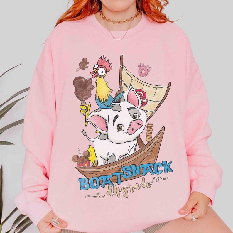 May include: Pink sweatshirt featuring a cartoon illustration of a pig in a wooden boat with a sail. A rooster and various treats, including ice cream and donuts, are also depicted. The text "BOAT SNACK Upgrade" is printed below the boat.