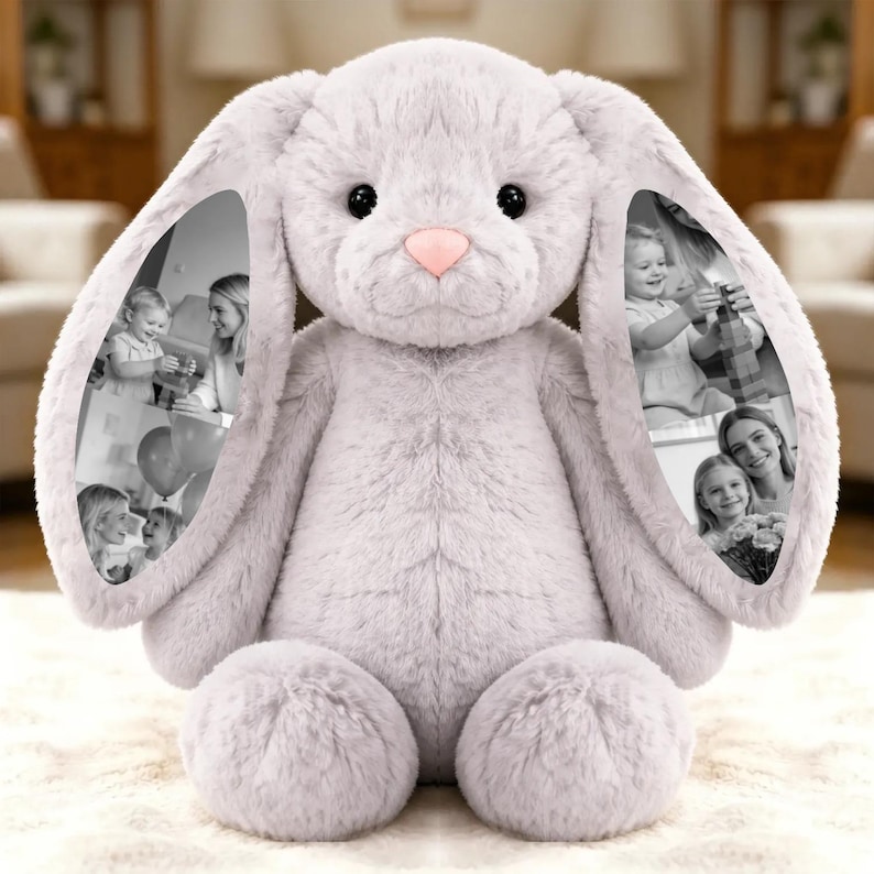 May include: A large, plush, light gray bunny rabbit stuffed animal with a pink nose and black eyes. The inside of each ear features a black and white photo collage. The bunny is sitting on a white, textured surface.