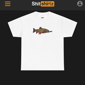 May include: White t-shirt with a detailed illustration of a fish with brown, red, and yellow scales, holding a cigar. The shirt has a crew neck and short sleeves. The brand name "Shit shirtz" is printed at the top.
