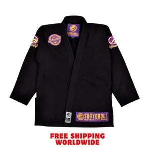Puede incluir: Uniforme negro de artes marciales con detalles morados y dorados. El uniforme presenta el nombre de la marca "SHOYOROLL" en el pecho, los hombros y el dobladillo inferior. El texto "FREE SHIPPING WORLDWIDE" aparece en rojo en la parte inferior.