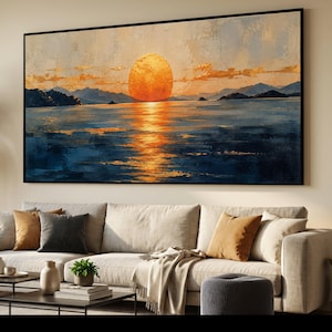 Op de afbeelding: Een groot rechthoekig wandkunstwerk met een olieverfschilderij van een zonsondergang boven kalm water. De scène toont een heldere oranje zon boven de horizon, met de reflectie daarvan glinsterend op het donkerblauwe water eronder.