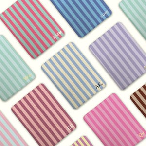 Può includere: Una collezione di oggetti rettangolari a righe in vari colori, tra cui rosa, blu e viola. Alcuni oggetti presentano iniziali o brevi parole come "com" e "AE". Gli oggetti hanno un aspetto morbido e strutturato.