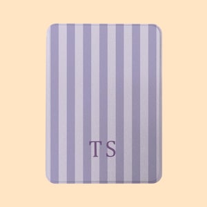 May include: A rectangular, lavender and white striped item with rounded corners. The item has the initials "TS" in the center. The background is a solid, light peach color.