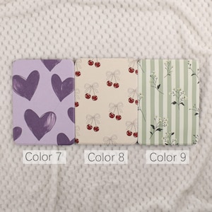 Puede incluir: Tres cuadernos estampados. El primero es lavanda con corazones morados oscuros. El segundo es crema con cerezas rojas y lazos. El tercero es verde y blanco a rayas con detalles florales. Cada cuaderno tiene una etiqueta con un n&uacute;mero de color.