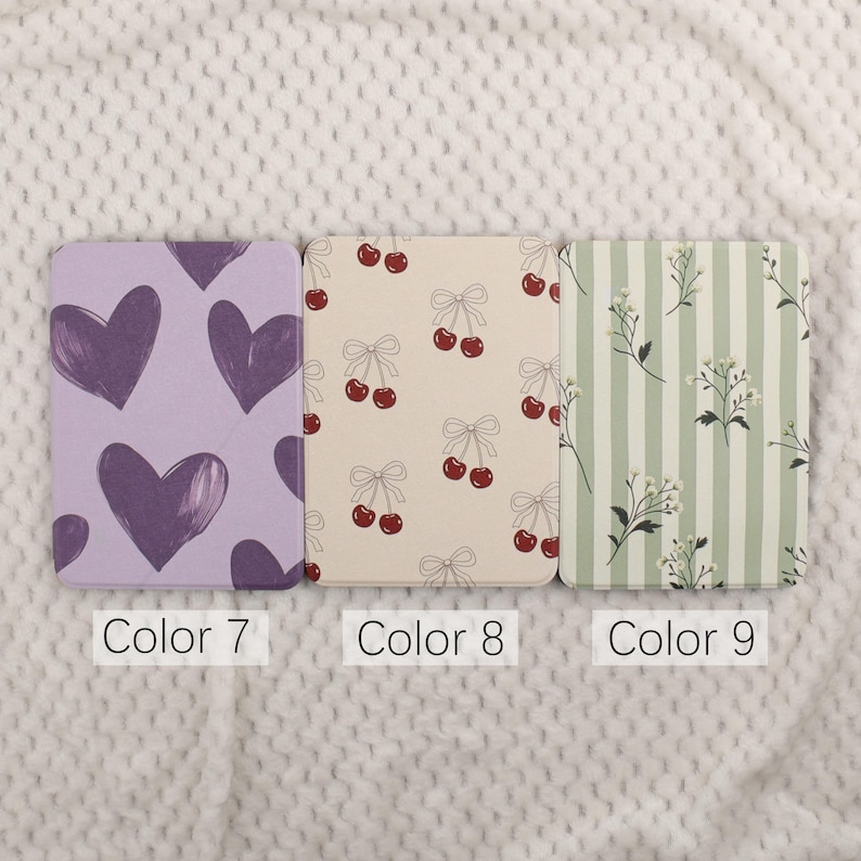 Puede incluir: Tres cuadernos estampados. El primero es lavanda con corazones morados oscuros. El segundo es crema con cerezas rojas y lazos. El tercero es verde y blanco a rayas con detalles florales. Cada cuaderno tiene una etiqueta con un n&uacute;mero de color.