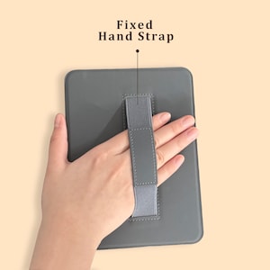 May include: A gray tablet case with a fixed hand strap. The text "Fixed Hand Strap" is above the strap. The case is rectangular with rounded corners. The hand strap is gray and elastic.