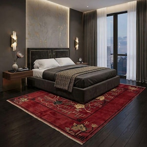 Puede incluir: Un dormitorio moderno con una cama gris oscuro, ropa de cama blanca y una manta estampada. Una alfombra roja con diseños florales se encuentra sobre el suelo de madera oscura. La habitación cuenta con paredes grises oscuras, apliques dorados y una gran ventana con cortinas transparentes.