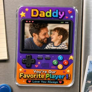 May include: A purple and orange magnet shaped like a retro handheld game console. The magnet features a photo of a father and son, with the text "Daddy" and "You're Our Favorite Player 1!" on the front.
