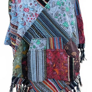 May include: A patchwork poncho with a hood and a front pocket. The poncho features various patterns, including mushrooms, stripes, and geometric designs, in shades of blue, red, green, and brown. The bottom edge is trimmed with fringe.