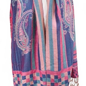 May include: A paisley patterned scarf in shades of blue, pink, and teal. The scarf features a large paisley design on the ends and vertical stripes in the center. The bottom edge has a checkered pattern and fringe.