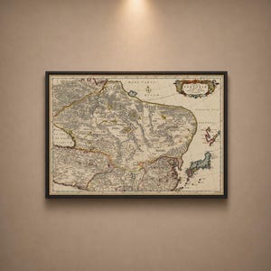 Puede incluir: Mapa antiguo enmarcado de Tartaria, con cartografía detallada y texto. El mapa está en un marco negro, exhibido contra una pared de tono neutro. Los colores del mapa incluyen beige, marrón y toques de rojo y verde.