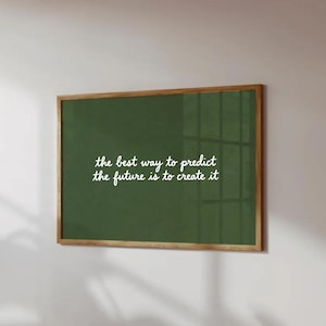 Puede incluir: Un cuadro enmarcado con un fondo verde oscuro y un marco de madera. El texto blanco en cursiva dice: "la mejor manera de predecir el futuro es crearlo."
