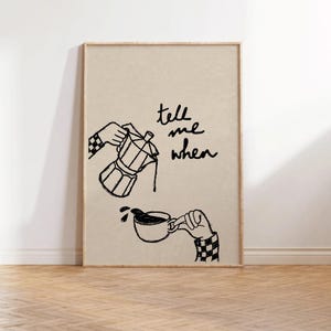 May include: A framed art print featuring a black and white illustration of coffee brewing. The image shows a moka pot pouring coffee into a cup, with the text "tell me when" in cursive. The hands are wearing checkered sleeves.