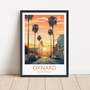 May include: A framed art print featuring a sunset street scene in Oxnard, California. The illustration depicts palm trees lining a road with cars, set against an orange and yellow sky. The text OXNARD CALIFORNIA is printed at the bottom.