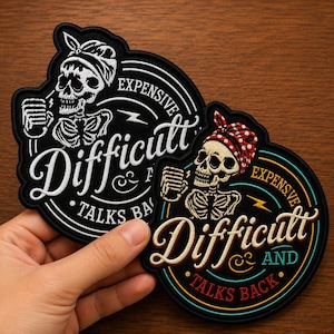 May include: Two circular embroidered patches featuring a skeleton wearing a bandana. The text reads "EXPENSIVE AND DIFFICULT TALKS BACK". One patch is black and white, while the other features a red polka-dot bandana with gold and teal accents.