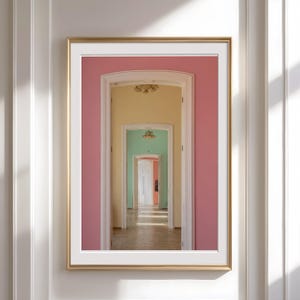 Puede incluir: Una impresión artística enmarcada que presenta una serie de arcos que retroceden en la distancia. Las paredes están pintadas en tonos de rosa, amarillo, verde y naranja, creando una perspectiva colorida. La obra de arte se muestra en un marco dorado.