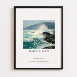 May include: A framed art print featuring a seascape painting by Julius Olsson titled After the Storm. The image depicts crashing ocean waves against dark rocks with a distant coastline. Text includes the artist name, exhibition details, and dates.