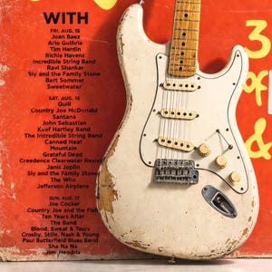 Vintage electric guitar with a concert listing featuring Jimi Hendrix and others.