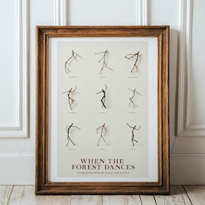 Könnte beinhalten: Ein gerahmter Druck mit neun Strichmännchen in Tanzposen. Das Kunstwerk trägt den Titel "When the Forest Dances" und wurde von Wind, Sun & Rain choreografiert. Der Rahmen ist warmbraun, der Hintergrund hellbeige.