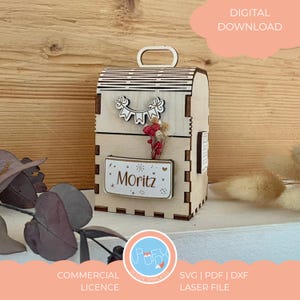 May include: A laser-cut wooden box with a handle, decorated with a banner and flowers. The name "Moritz" is displayed on a small rectangular plaque. The box is a digital download, with a commercial license for SVG, PDF, and DXF laser files.